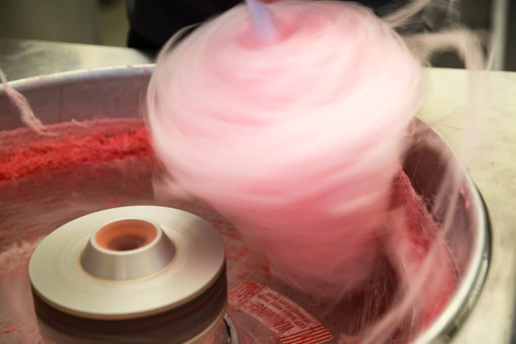 Pink cotton candy spinning fast as it is being made in a machine.