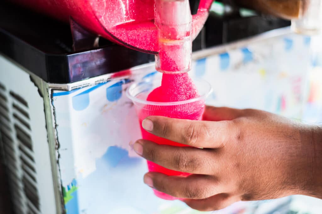 Human hand serving slushy drink from slushy  machine