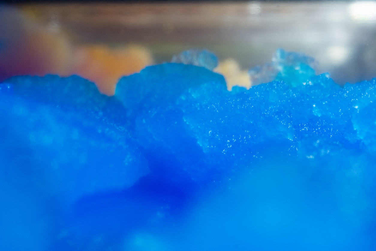 Close up blue slush in a slush making machine with other flavor color in the backdrop